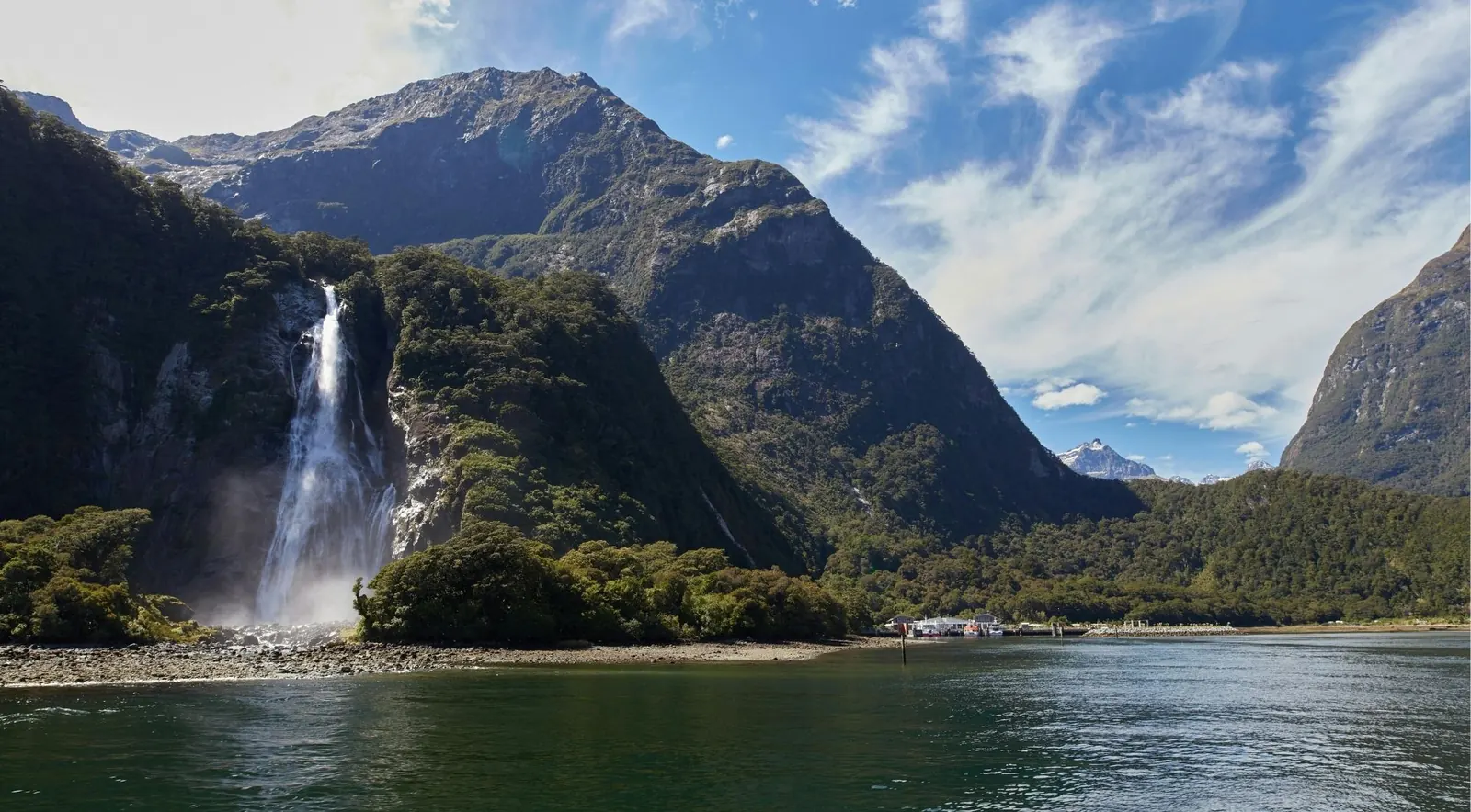 Bowen Falls cascading beside Milford Sound's harbour and boat wharf