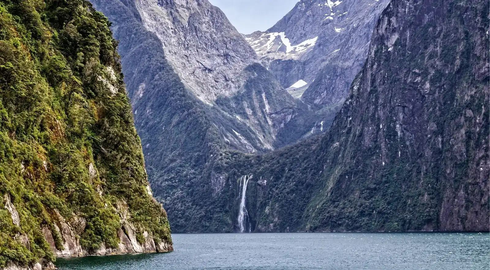 Bowen Falls and Milford Sound's harbour wharf seen across the fjord